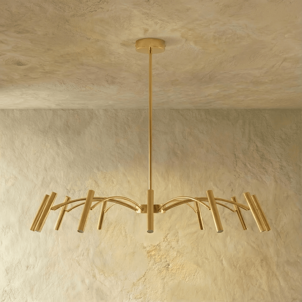 A brass-toned version of the chandelier shows its arched arms and cylindrical heads in a mid-density spread, Clérachic studio hero shot.