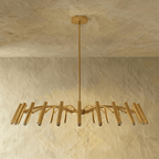 The fullest brass-toned chandelier spread shows dense arched arms and tube heads against a plain backdrop in this Clérachic hero shot.