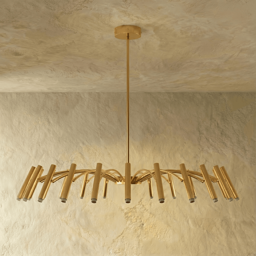 The fullest brass-toned chandelier spread shows dense arched arms and tube heads against a plain backdrop in this Clérachic hero shot.