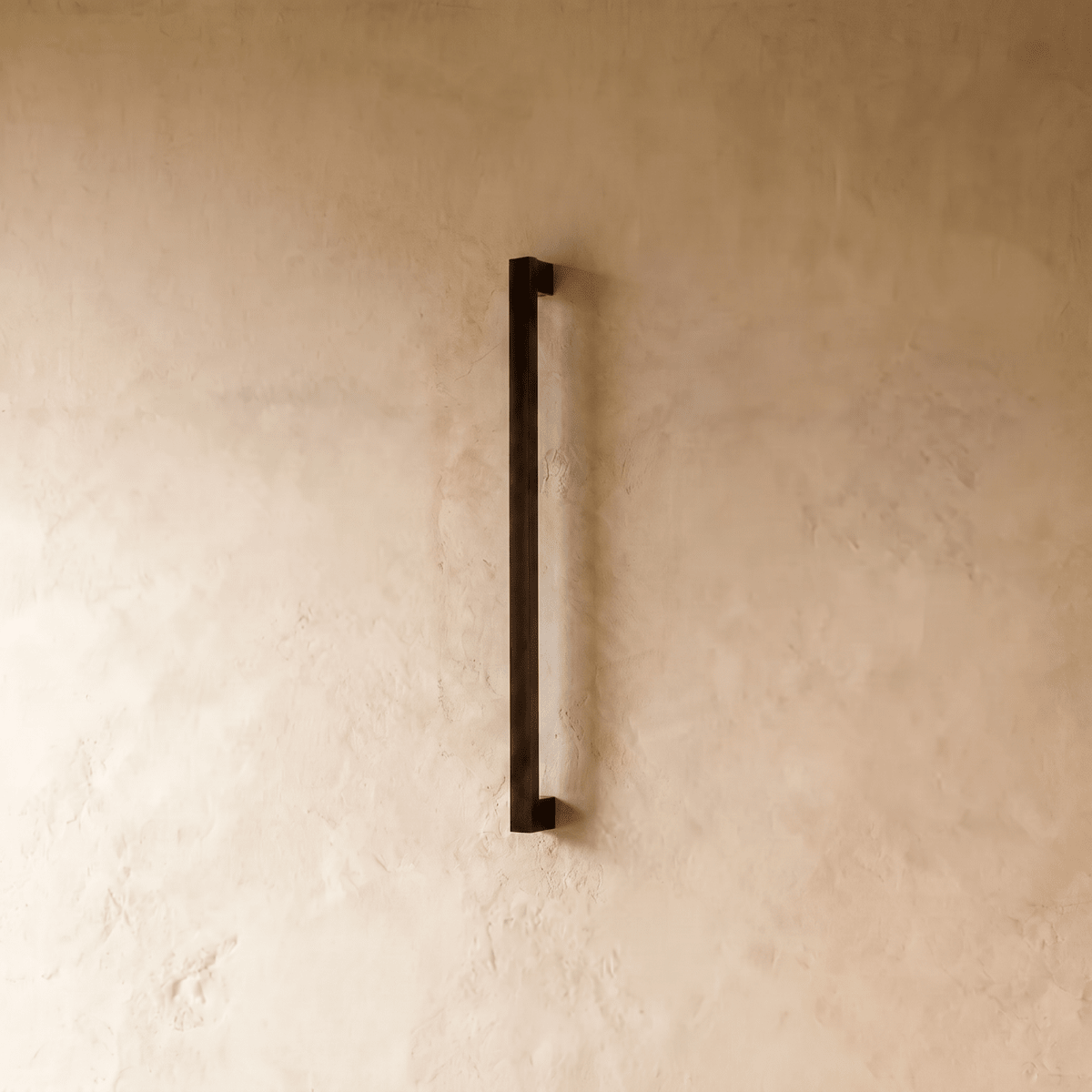 The slim black column wall light is shown unlit, its square profile against a plain plaster wall in this Clérachic hero shot.