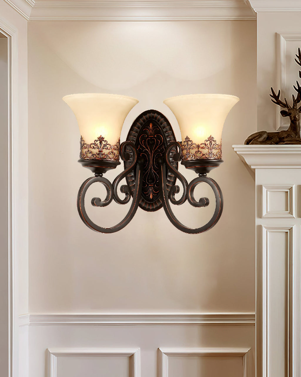 A two-arm Clérachic wall lamp on a cream panelled wall, beside a white mantel with a small stag figure.