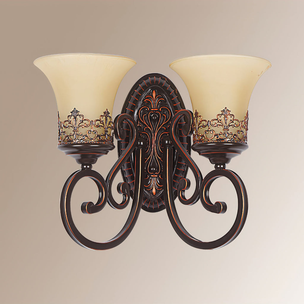 Front view of a two-arm Clérachic wall lamp on a beige backdrop, showing the oval backplate and the scrolled arms.