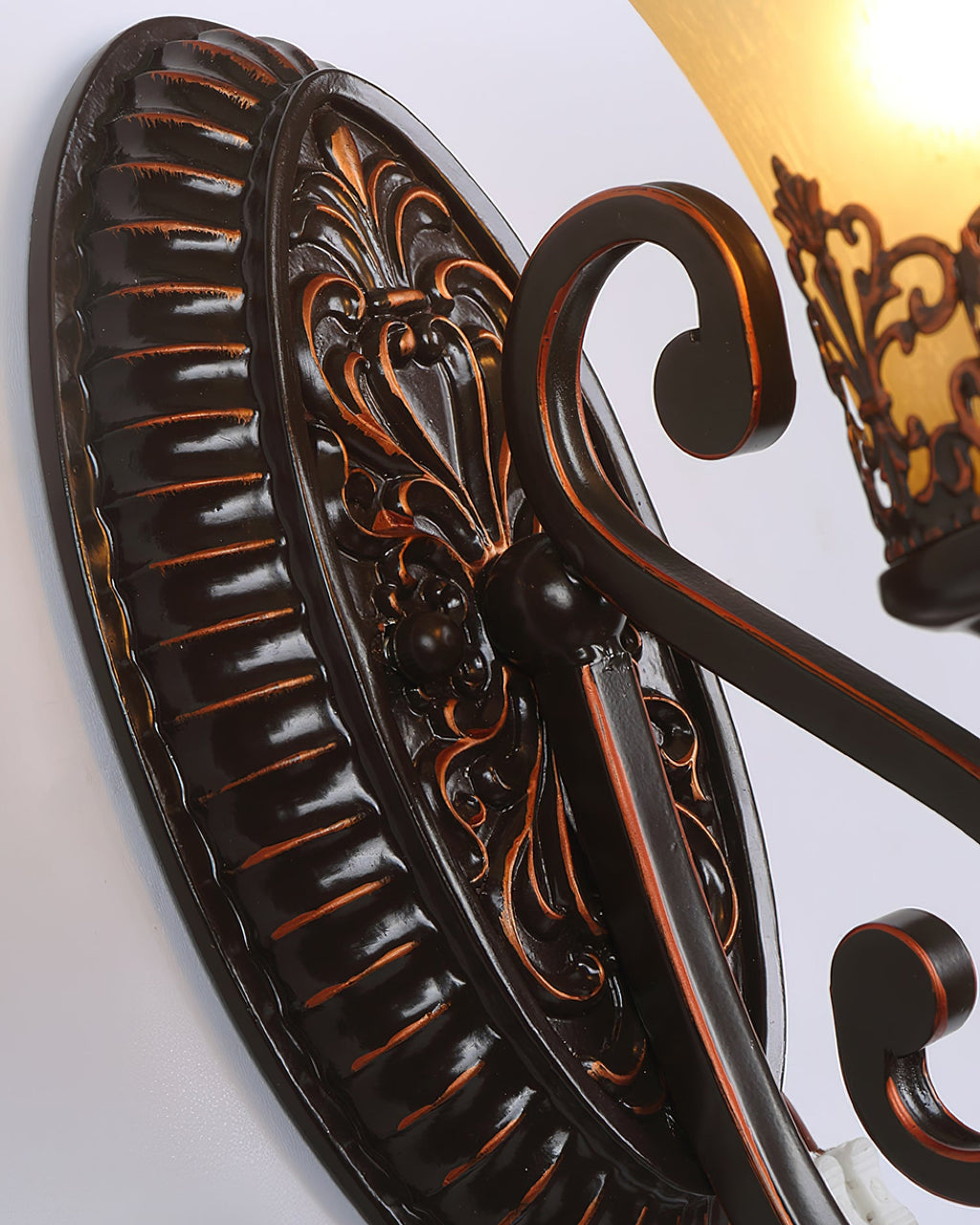 Close view of the ribbed oval backplate of this Clérachic wall lamp, with a scrolled arm and a shade above.