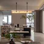 Wide dining room view of the Clérachic Black Linear Chandelier lighting a marble table set with chairs and a bench.