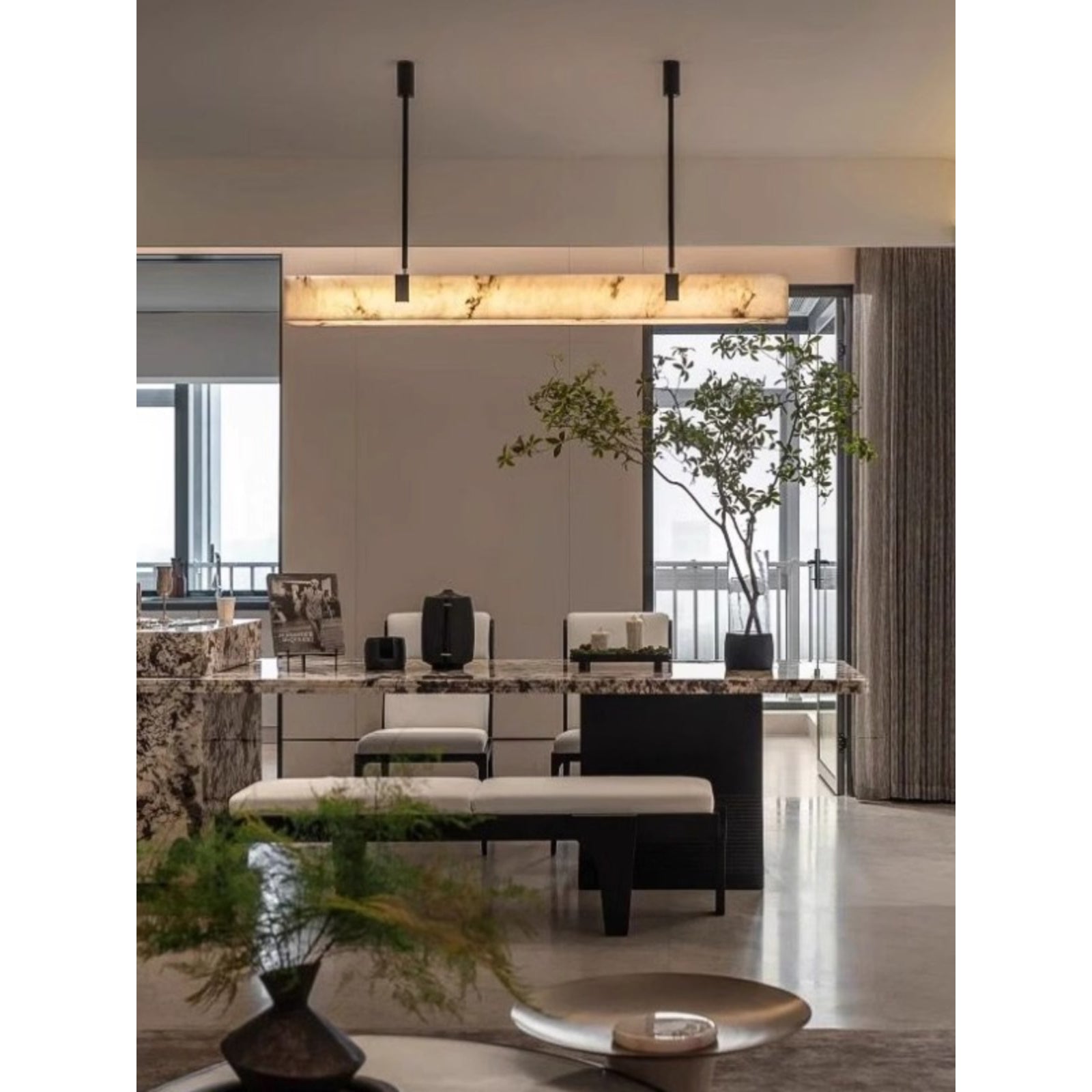 The Clérachic Black Linear Chandelier illuminates an open dining and kitchen space with plants and a marble island.