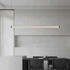 Above a dark dining table with black leather chairs, this Clérachic linear pendant glows warm in front of a pale niche wall.