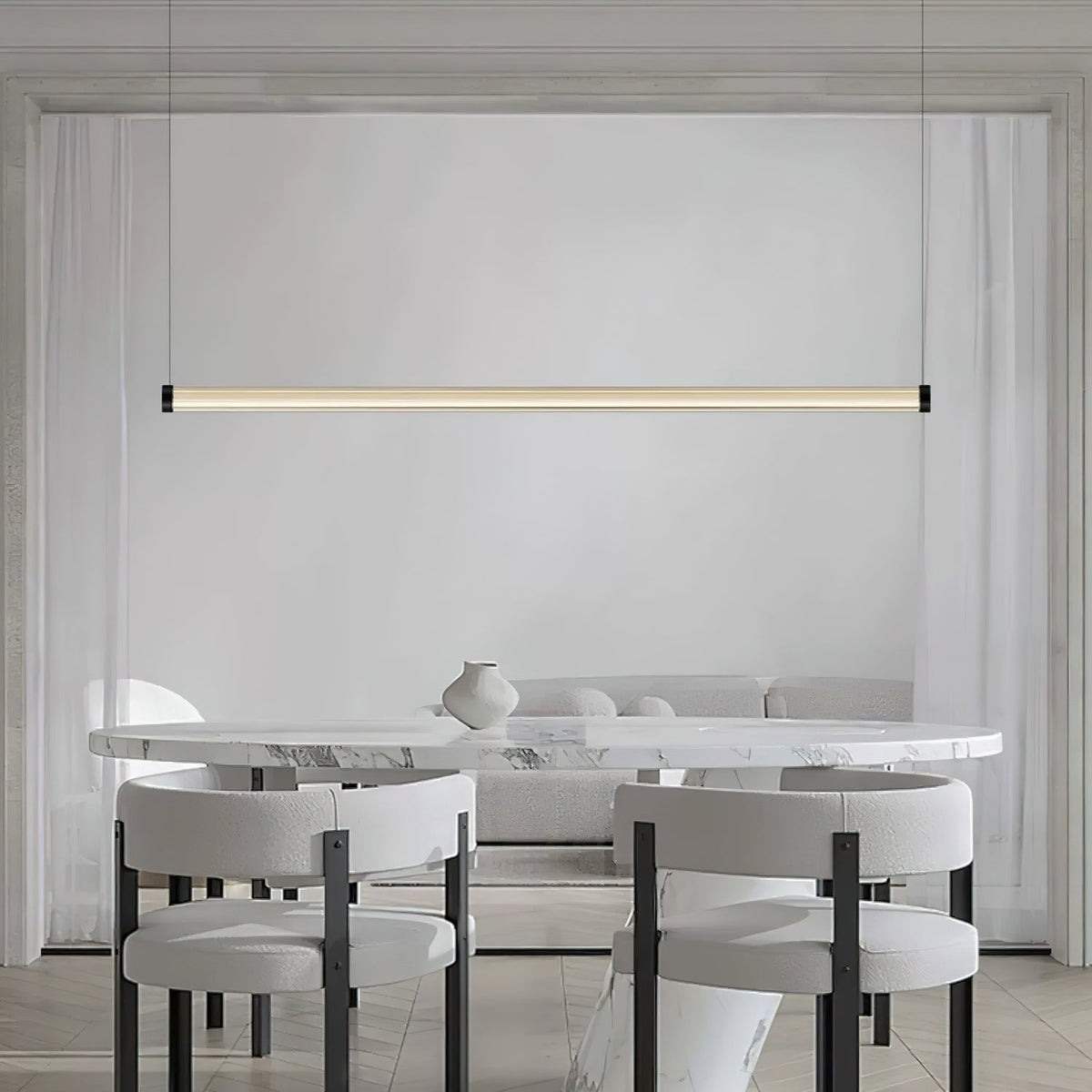 This Clérachic linear pendant hangs over a marble oval table with boucle chairs, its slim lit tube running across a pale panelled wall.