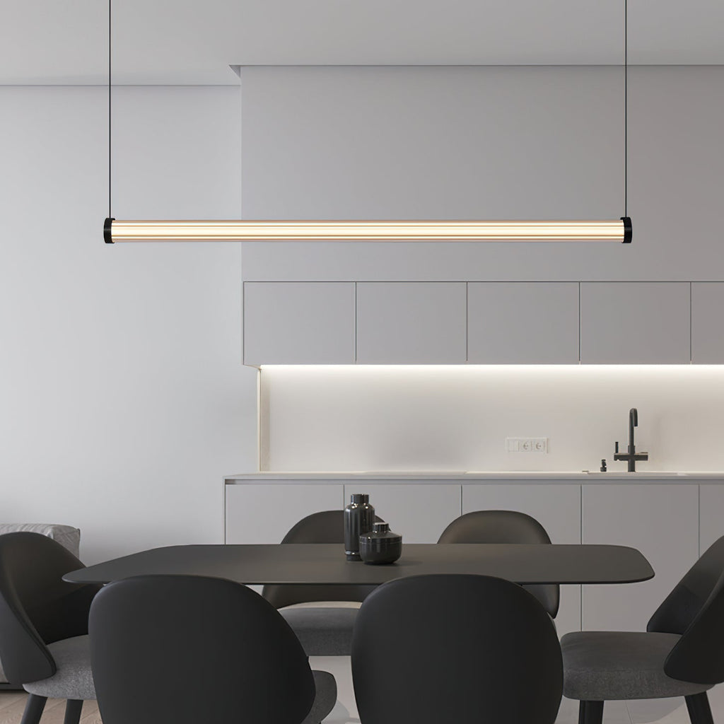 Over a dark rectangular table with black shell chairs, this Clérachic linear pendant hangs level in front of a kitchen with a lit backsplash.
