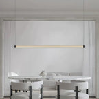 A Clérachic linear pendant lit above a marble table with white boucle chairs and a small vase, its tube centred on a pale wall.