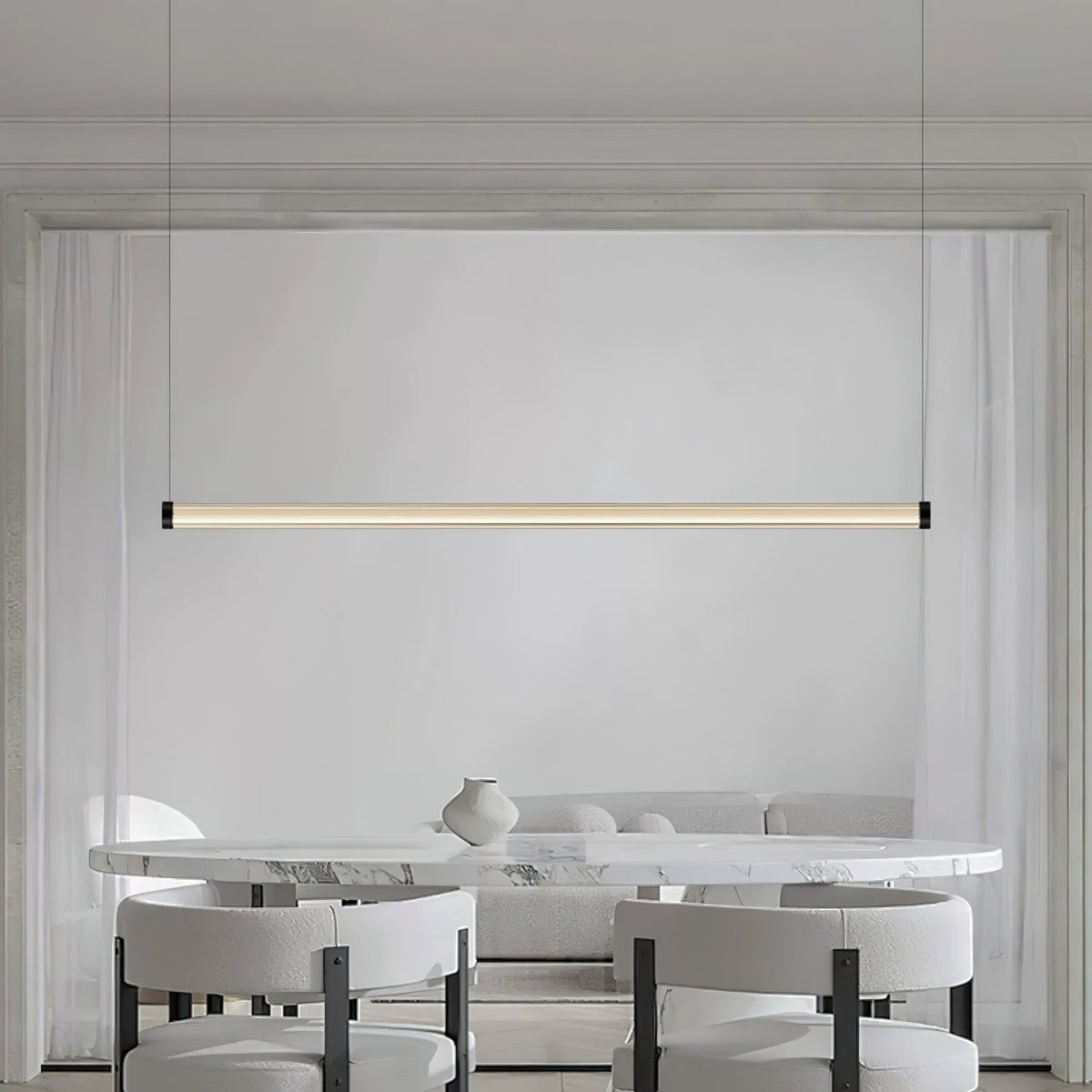 A Clérachic linear pendant lit above a marble table with white boucle chairs and a small vase, its tube centred on a pale wall.