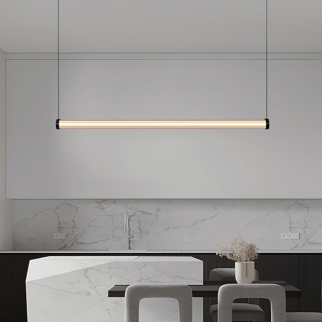 This Clérachic linear pendant hangs in front of a marble kitchen splashback and an angular stone island with grey stools.