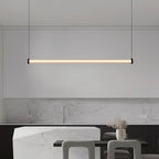 This Clérachic linear pendant hangs in front of a marble kitchen splashback and an angular stone island with grey stools.