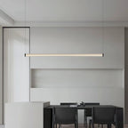 Warm light glows from this Clérachic linear pendant above a black dining table, in front of a pale grey wall niche.