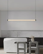 Hanging in front of a marble splashback and a stone island with grey chairs, this Clérachic linear pendant glows a soft warm white.