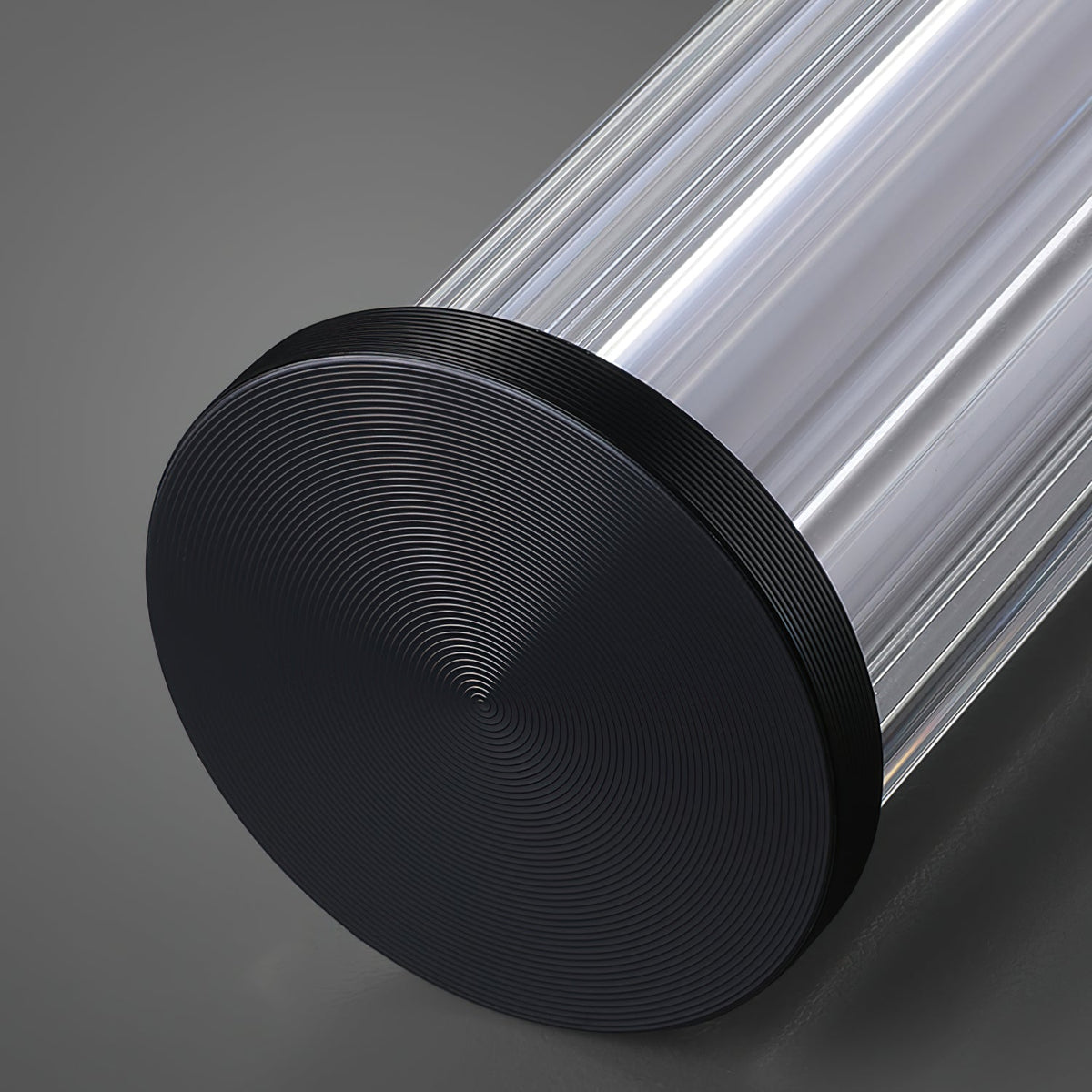 Close view of the black end cap on this Clérachic linear pendant, with fine concentric rings and the ribbed clear tube behind it.