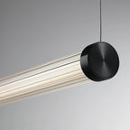 A Clérachic linear pendant on a pale grey backdrop, its black end cap with a ringed finish hung from a thin dark cable.