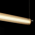 In the dark, this Clérachic linear pendant glows warm, the ribbed clear tube lit from within and hanging from a thin cable.