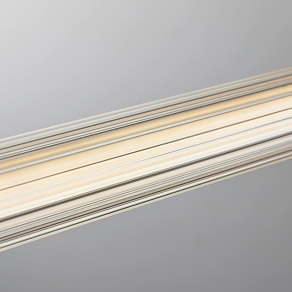 Close view of the vertical ribbing on the clear tube of this Clérachic linear pendant, lit warm from inside.