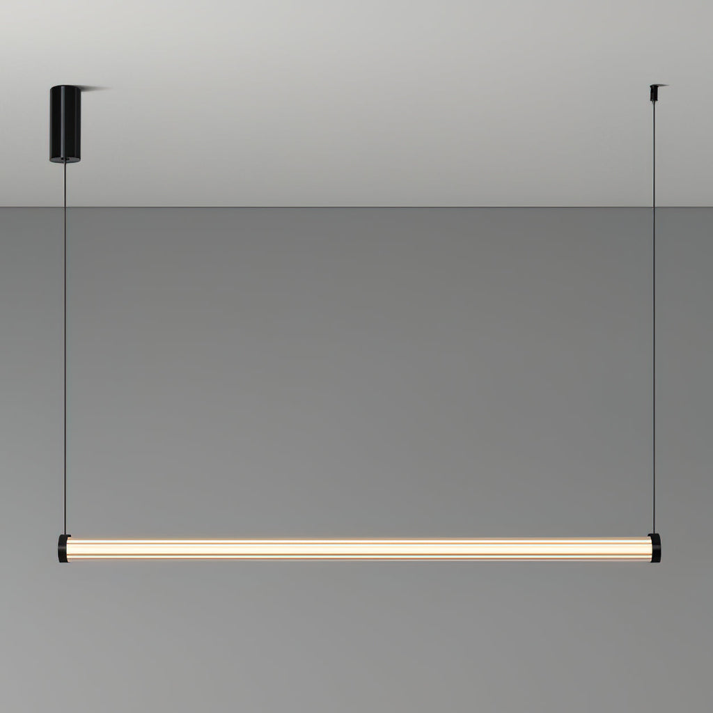 A Clérachic linear pendant lit on a grey backdrop, hung level from two thin cables, with a black cylinder canopy on the left.