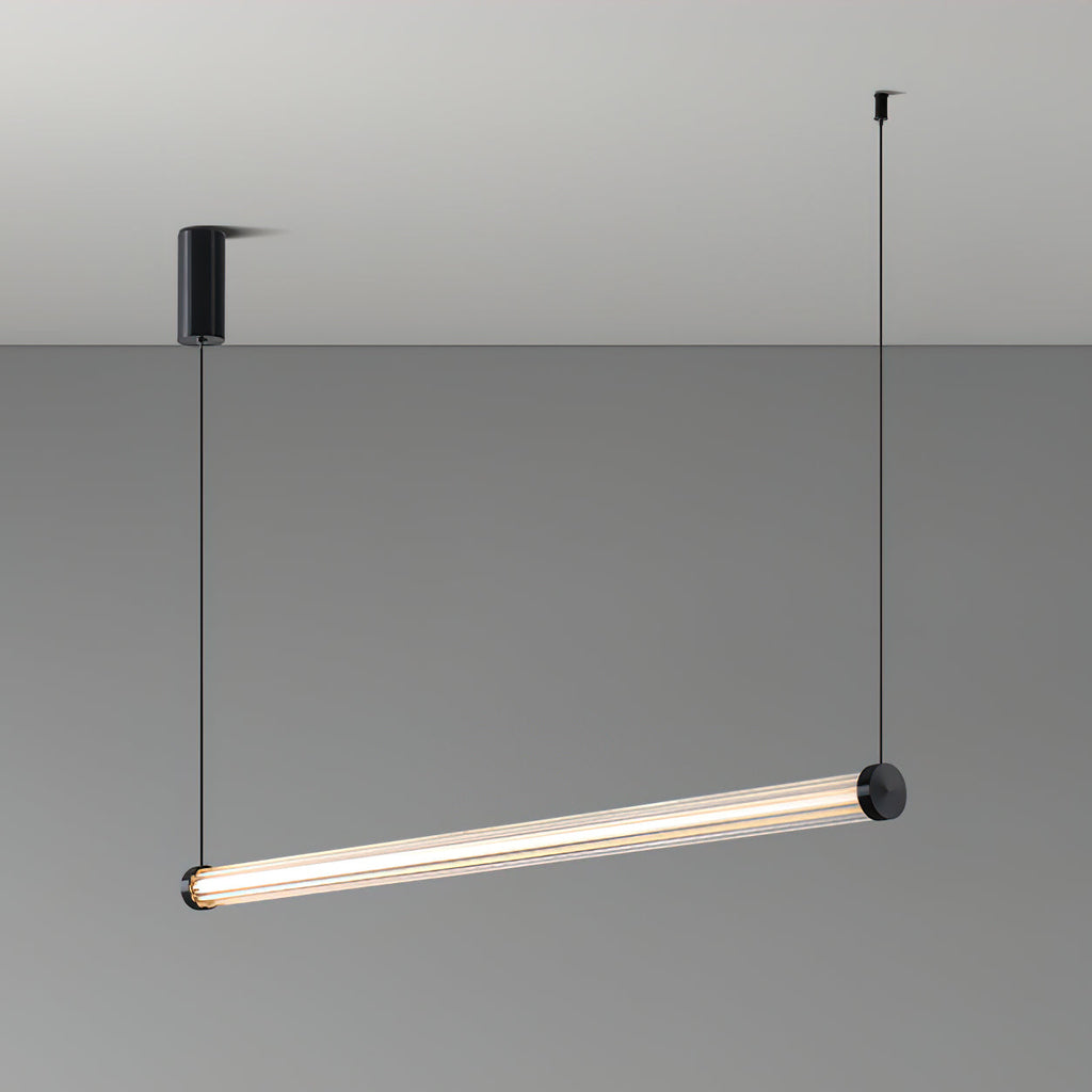 This Clérachic linear pendant hung at a tilt on a grey backdrop, with a black canopy on the left and one cable at each end.