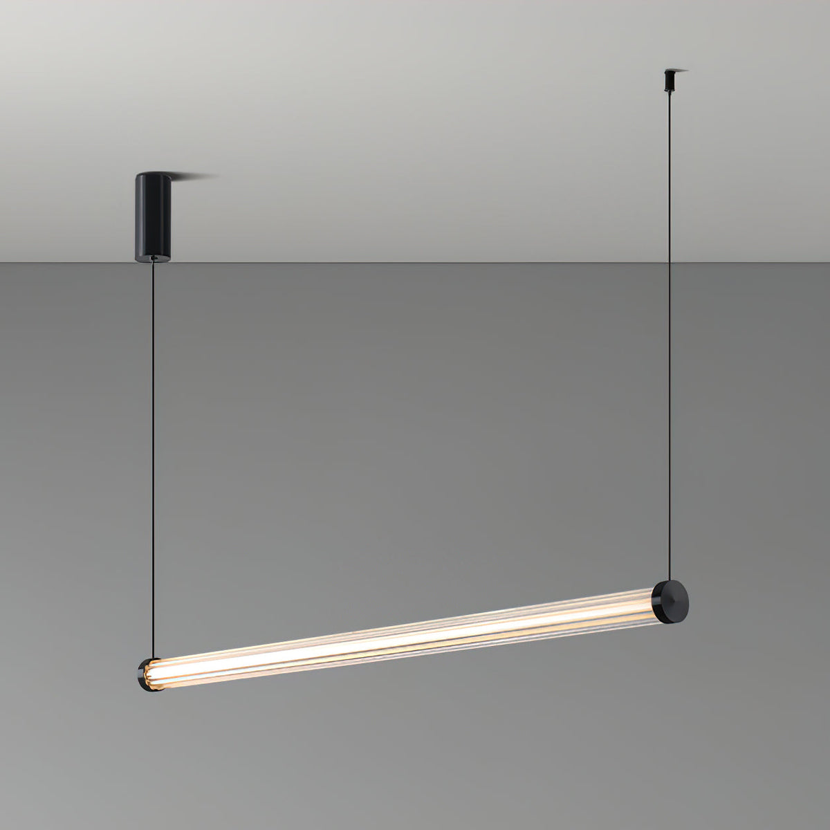 This Clérachic linear pendant hung at a tilt on a grey backdrop, with a black canopy on the left and one cable at each end.