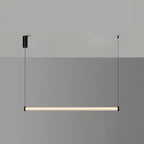 A Clérachic linear pendant lit warm on a two-tone grey wall, hung level from two cables with a black canopy on the left.