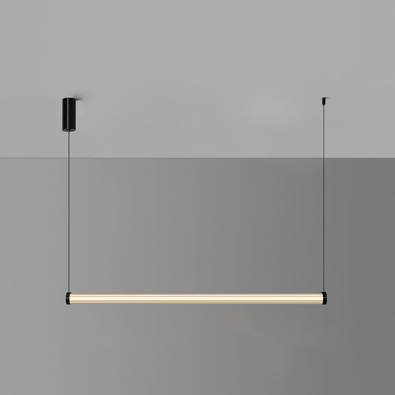 A Clérachic linear pendant lit warm on a two-tone grey wall, hung level from two cables with a black canopy on the left.