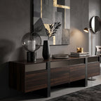 On a dark wood sideboard in front of a gold and grey abstract artwork, this Clérachic table lamp stands beside a black vase.