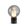 Larger cut-out view of this Clérachic table lamp, the cut-away globe showing the glowing white cylinder over a black marble plinth.
