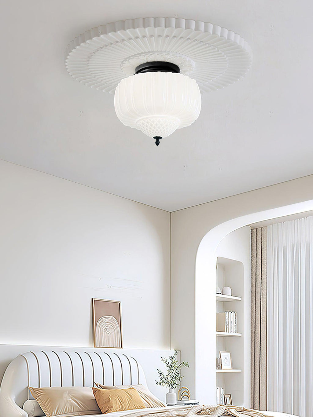 White ribbed glass ceiling light from Clérachic hung from a decorative plaster rose, above a bedroom with an arched alcove.