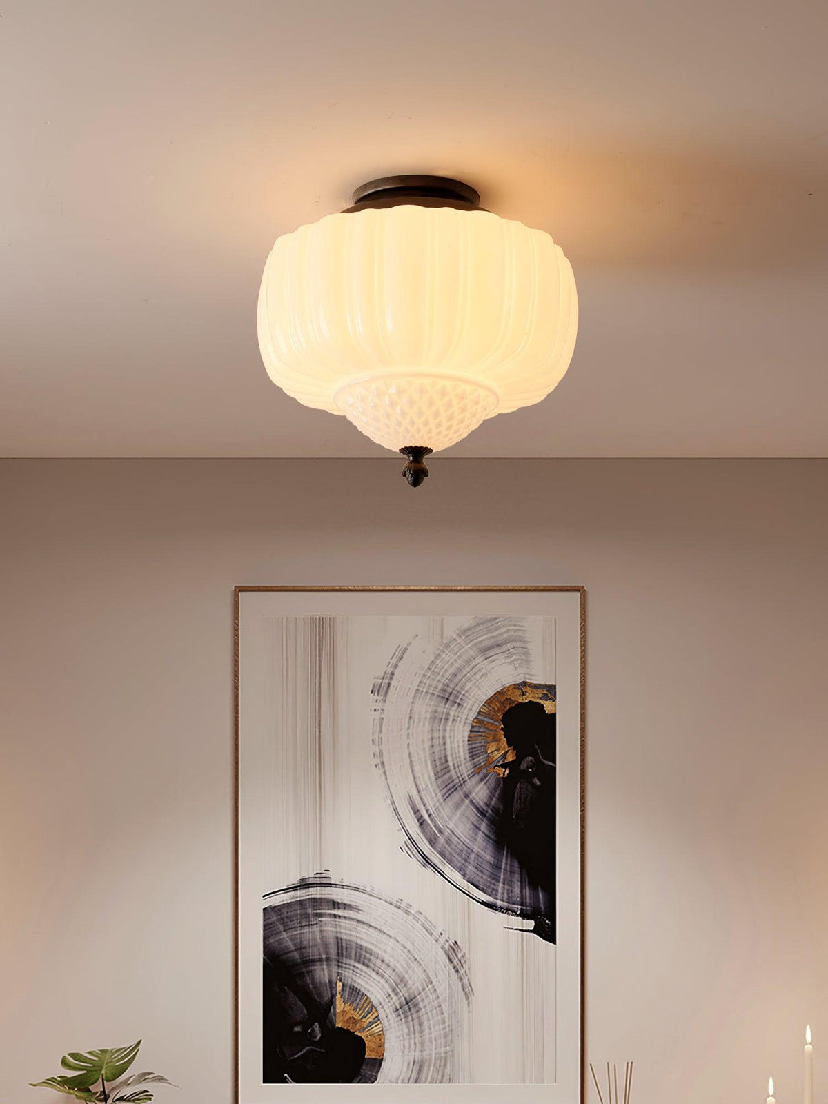 Lit ribbed glass ceiling light from Clérachic with a warm glow, above a wall with a large abstract painting in black and gold.