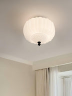 Ribbed white glass ceiling light from Clérachic on a cream ceiling, with a window and soft curtains beside it.