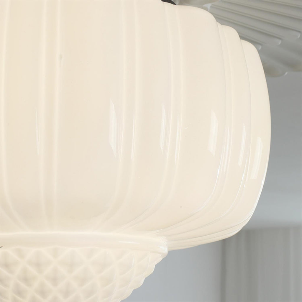 Close view of the fluted milk glass on this Clérachic ceiling light, lit warm, with the quilted bowl at the bottom.