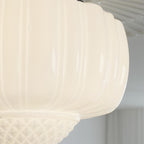 Close view of the fluted milk glass on this Clérachic ceiling light, lit warm, with the quilted bowl at the bottom.