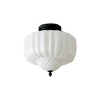 Ribbed white glass ceiling light from Clérachic with a black round canopy and a small finial, on a white backdrop.