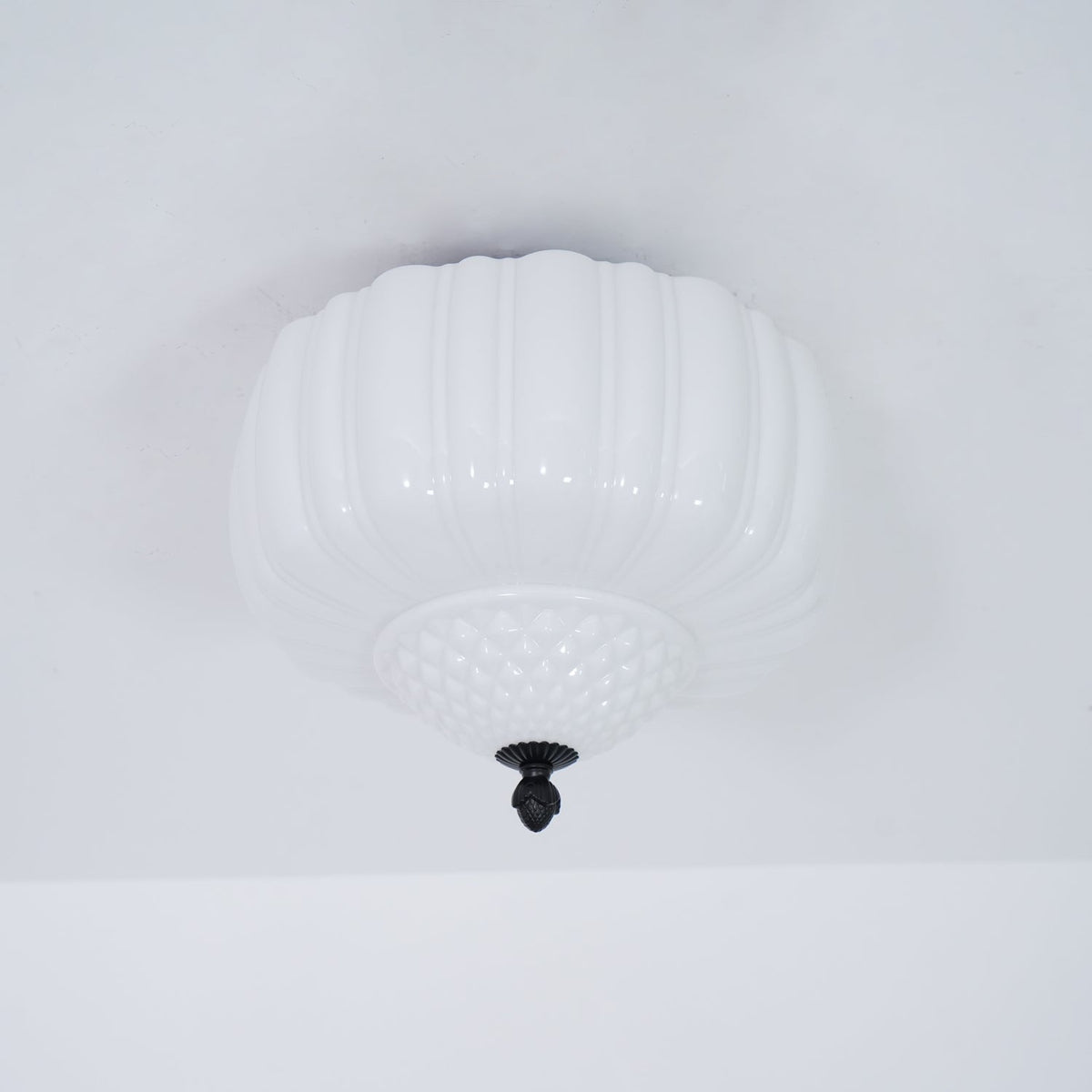 Unlit ribbed white glass ceiling light from Clérachic with a quilted lower bowl, seen from below on a pale ceiling.