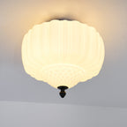 Close, lit view of the ribbed glass shade on this Clérachic ceiling light, with a warm glow spreading across the ceiling.