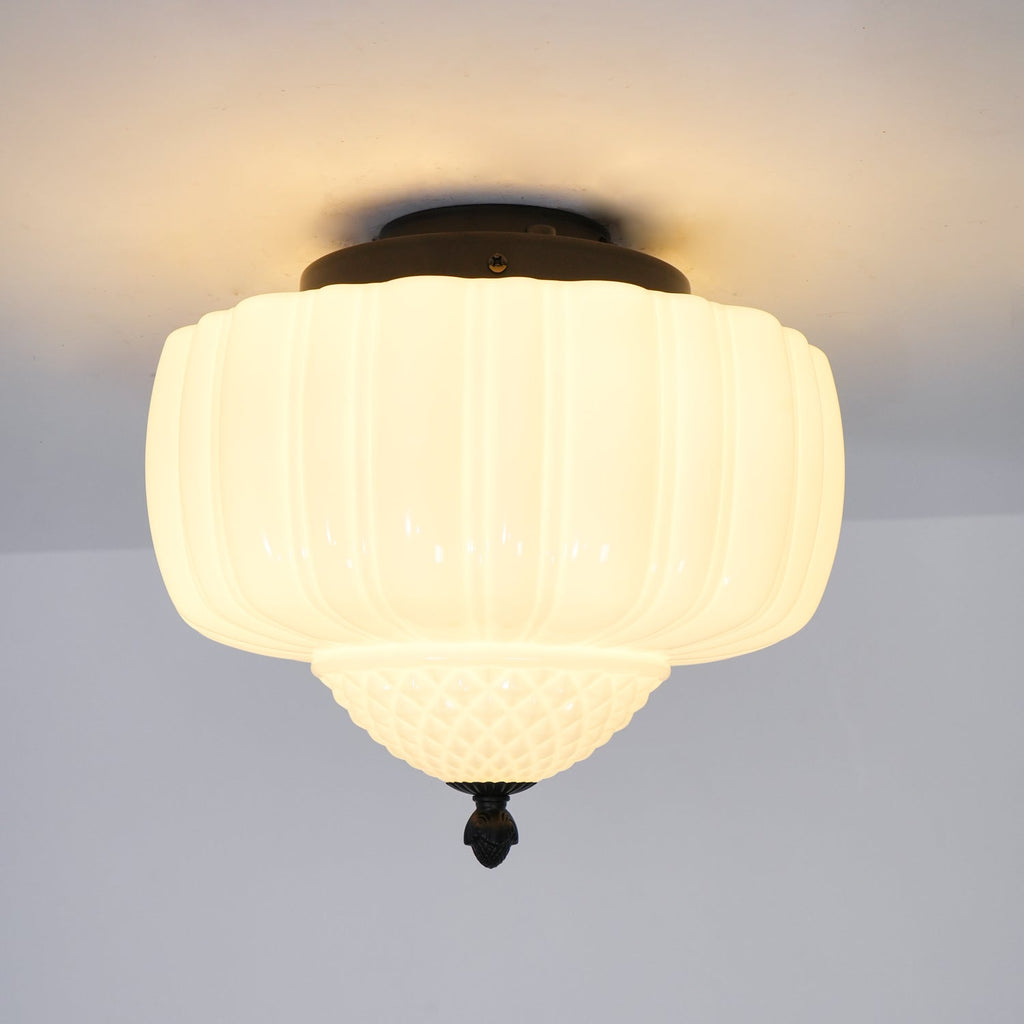 Lit white glass ceiling light from Clérachic with a black canopy, seen from below with its quilted bowl and finial.