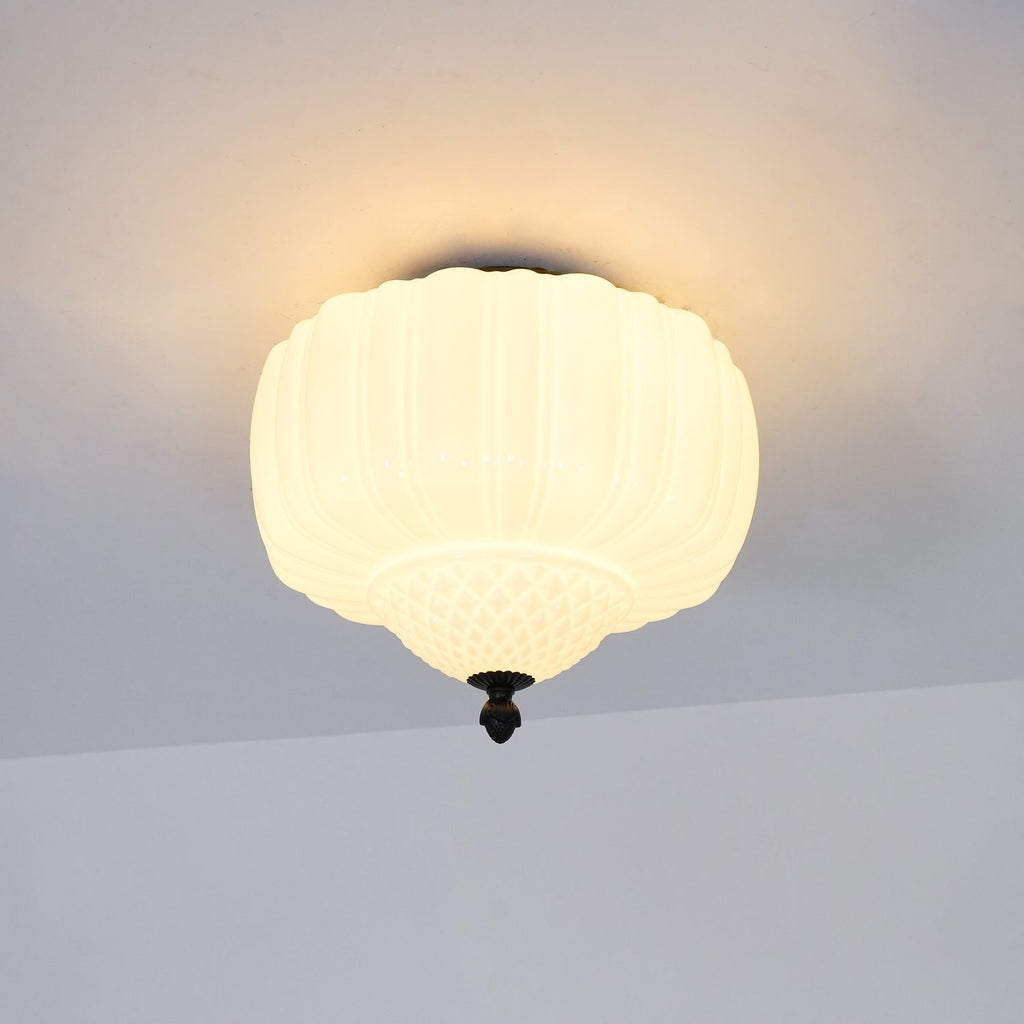 Warm-lit ribbed glass ceiling light from Clérachic with a black canopy, hung flush to a pale ceiling.
