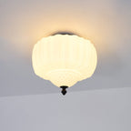 Warm-lit ribbed glass ceiling light from Clérachic with a black canopy, hung flush to a pale ceiling.
