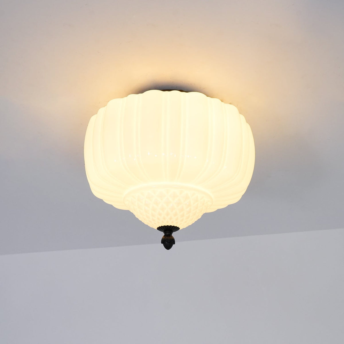 Warm-lit ribbed glass ceiling light from Clérachic with a black canopy, hung flush to a pale ceiling.