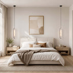 A pair of Clérachic capsule pendants hung as bedside lights on either side of a low bed with a taupe throw and a framed print.