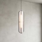 Close view of a Clérachic capsule pendant with a textured grey shade and a lit strip inside, against a plastered wall.
