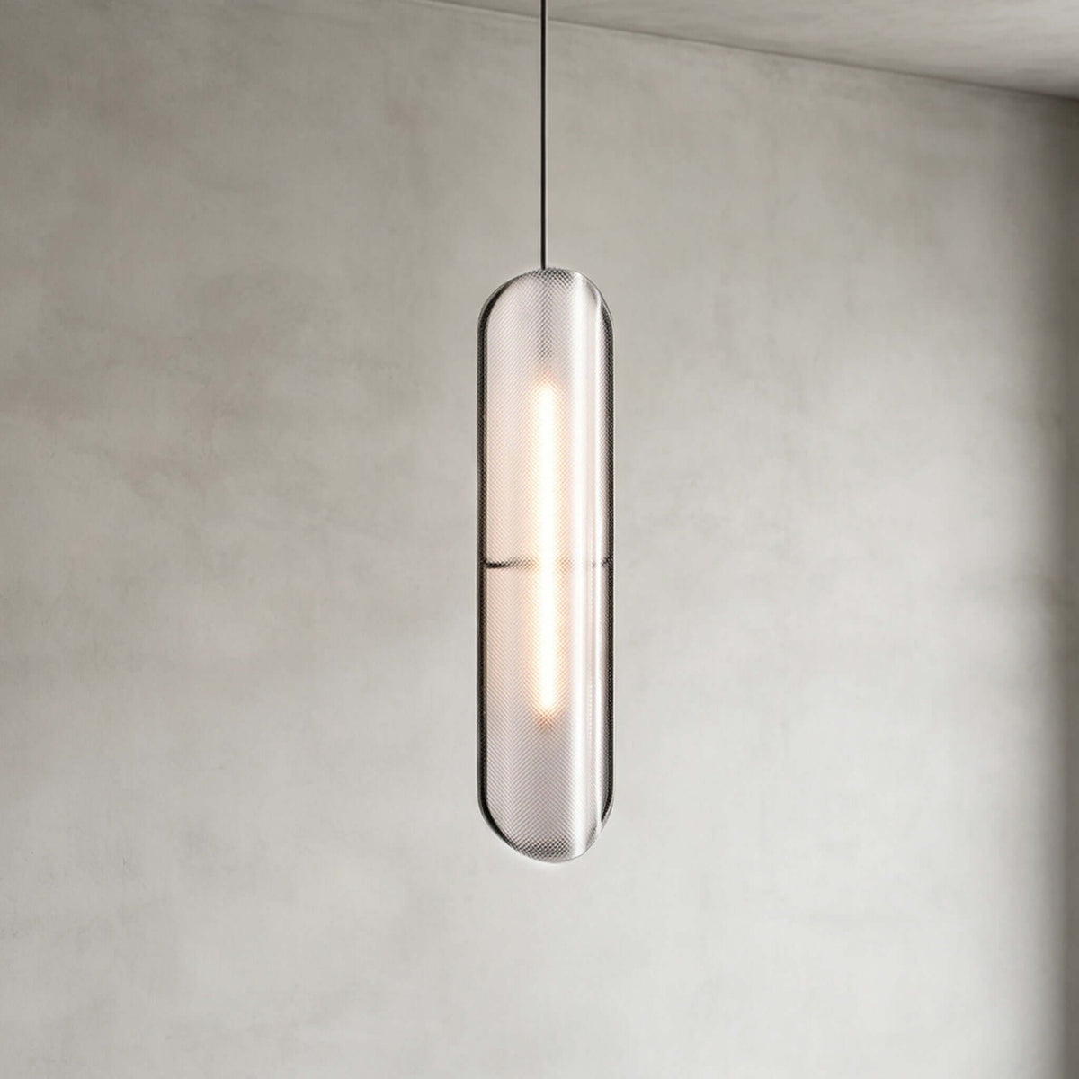 Close view of a Clérachic capsule pendant with a textured grey shade and a lit strip inside, against a plastered wall.
