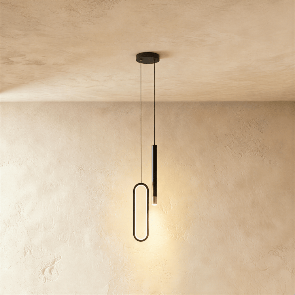 A black pendant light pairs a slim oval acrylic ring with a cylindrical rod head, hanging from a shared canopy in this Clérachic hero shot.