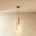A black pendant light pairs a slim oval acrylic ring with a cylindrical rod head, hanging from a shared canopy in this Clérachic hero shot.