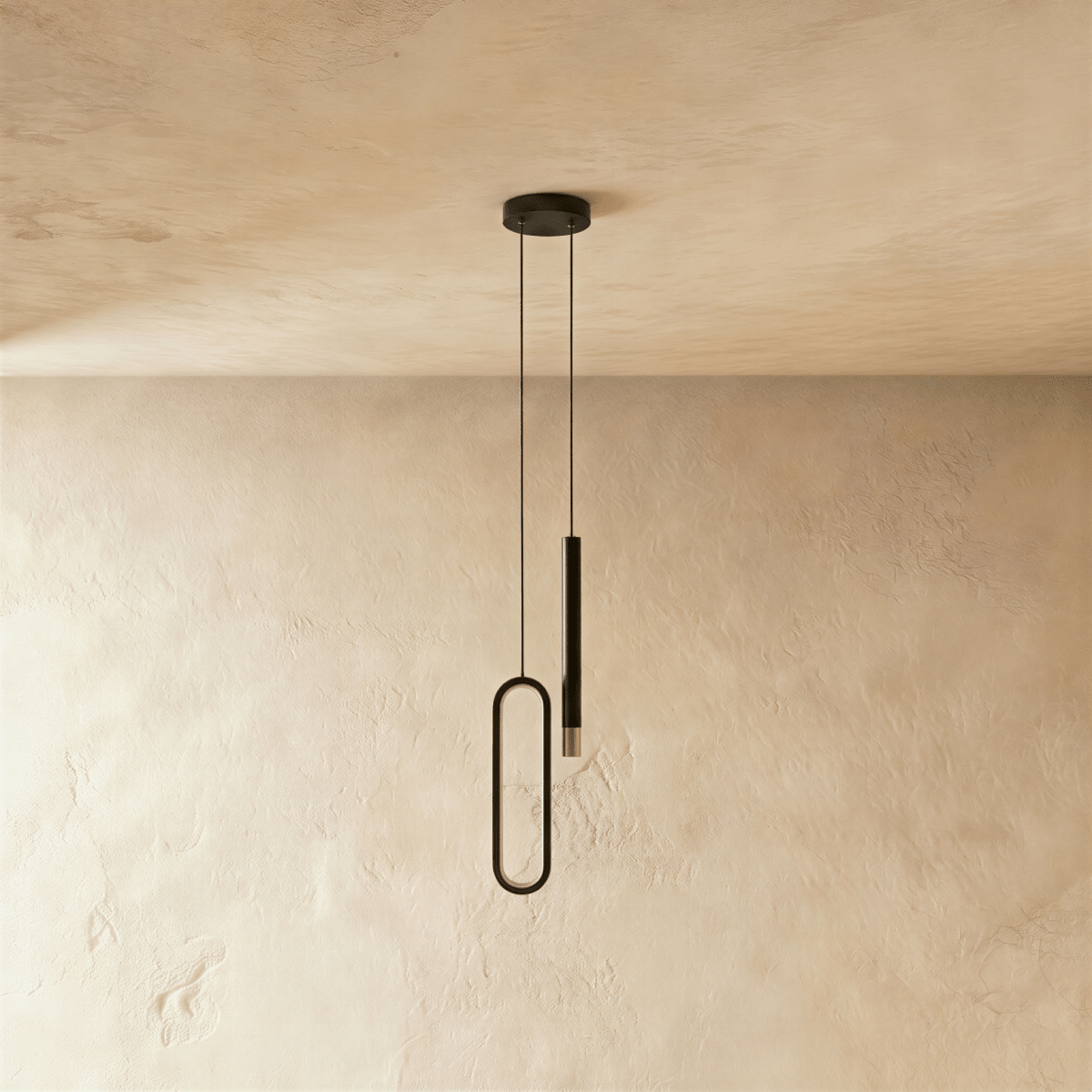 Seen from another angle, the black pendant's oval acrylic ring and rod head hang side by side against a plaster wall, Clérachic hero shot.