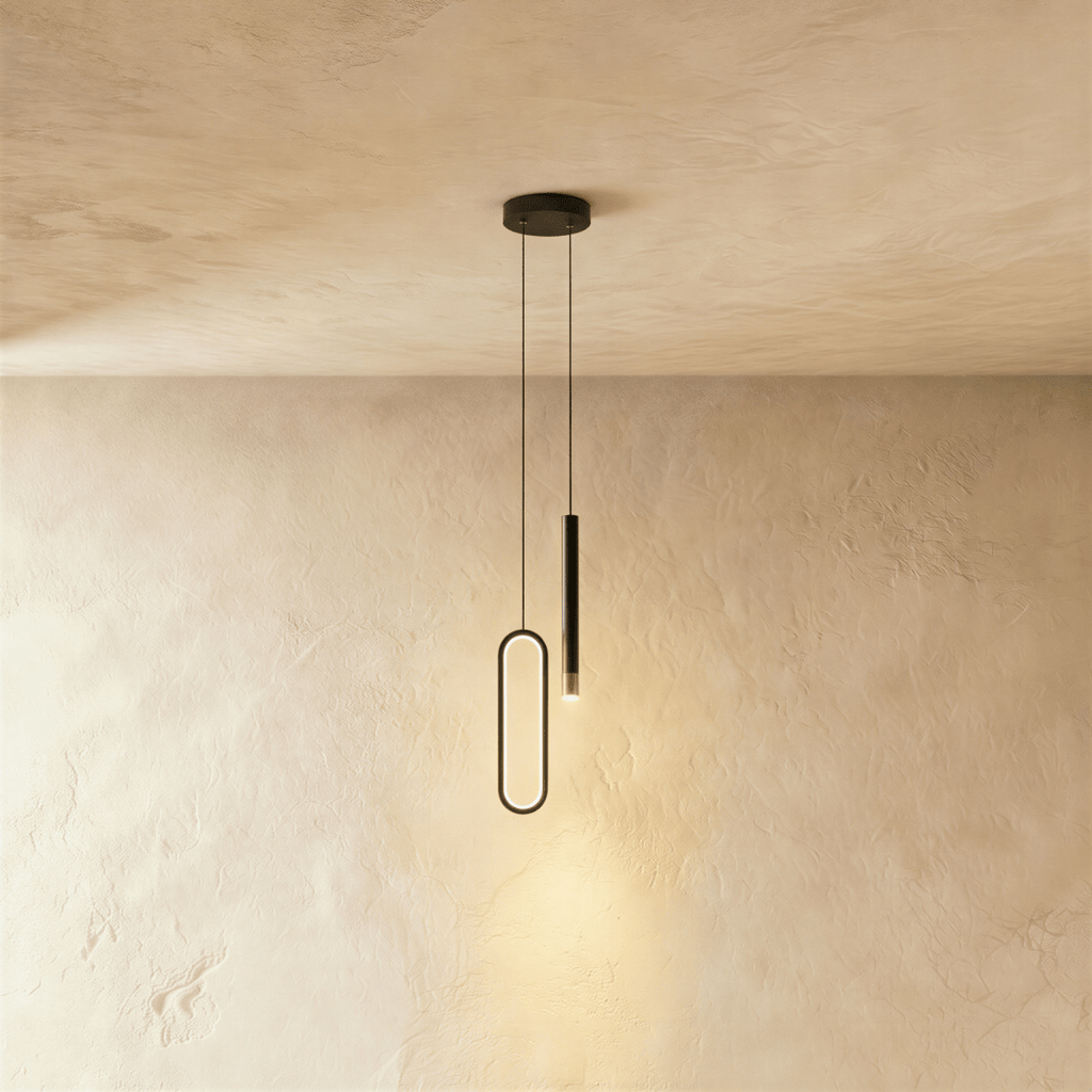 The black pendant's oval ring and cylindrical rod are shown together once more against a bare plaster backdrop, Clérachic hero shot.