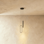 The black pendant's oval ring and cylindrical rod are shown together once more against a bare plaster backdrop, Clérachic hero shot.