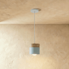 Clérachic pendant light with a light blue cylinder shade and walnut cap, suspended from a plain plaster ceiling.